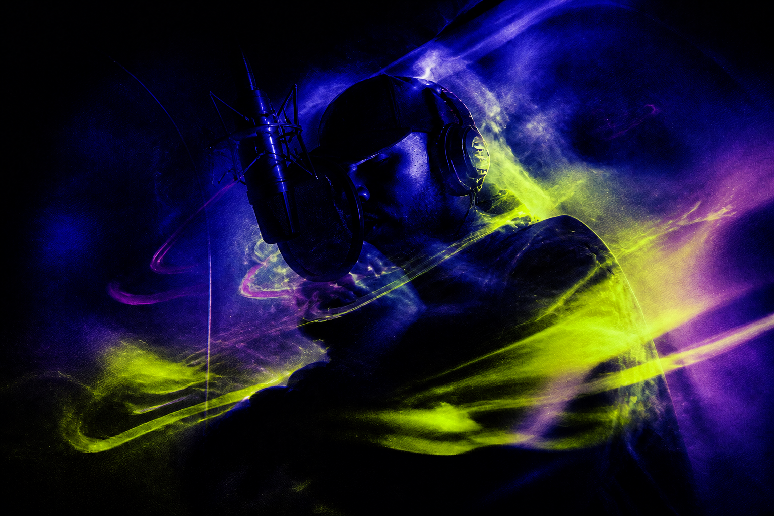 Rapper in headphones recording at a microphone under blue and yellow light